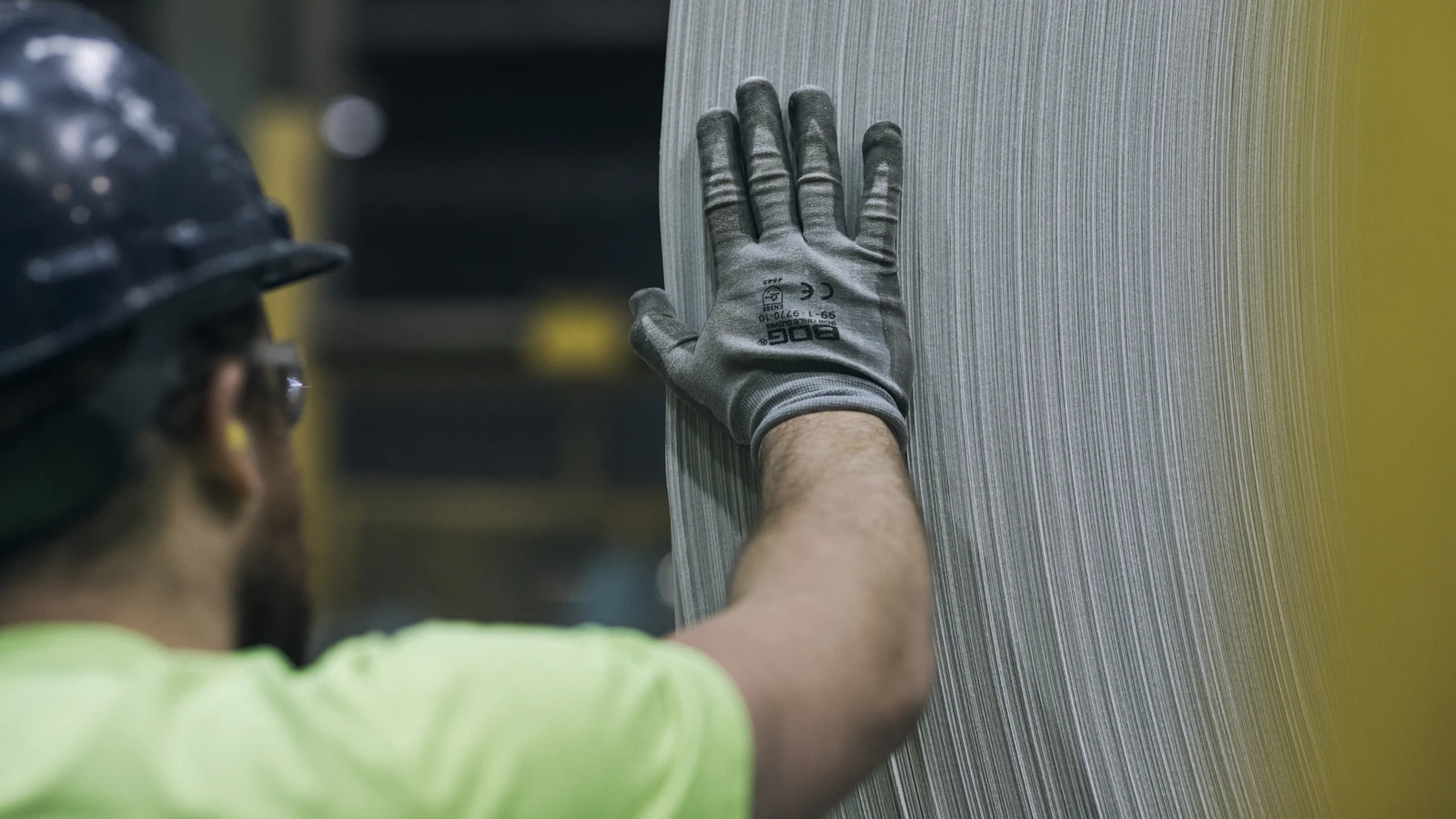 a man in a hard hat and safety gear working on a piece of metal