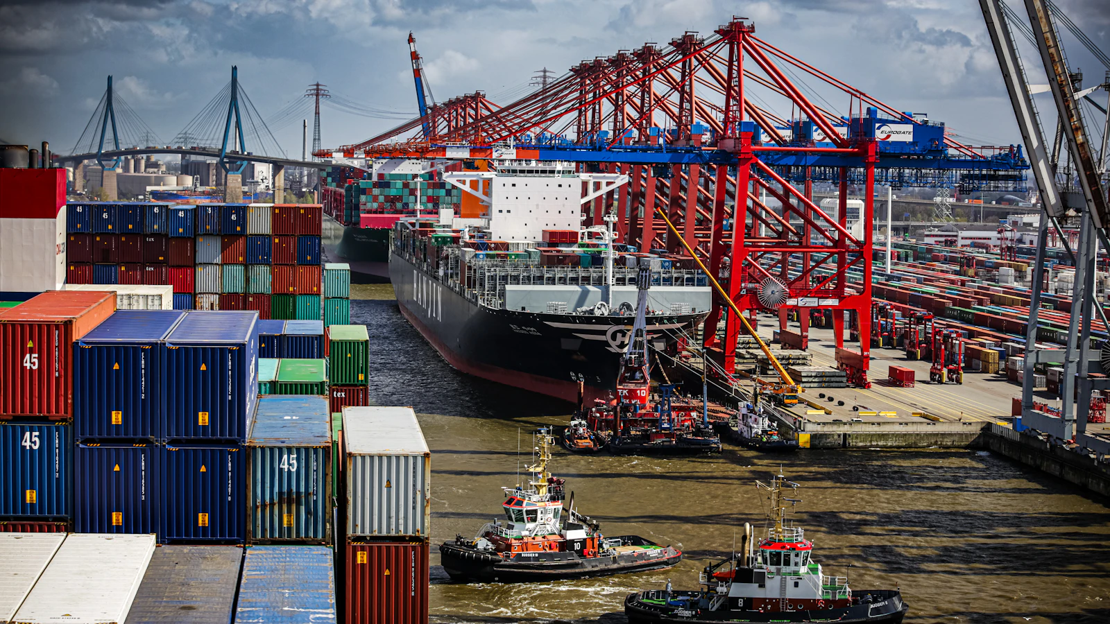a tug boat in the water next to a large cargo ship