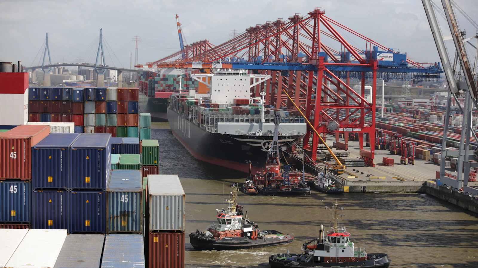 a tug boat in the water next to a large cargo ship