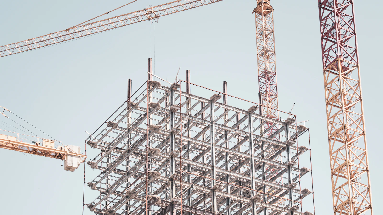 gray metal building frame near tower crane during daytime