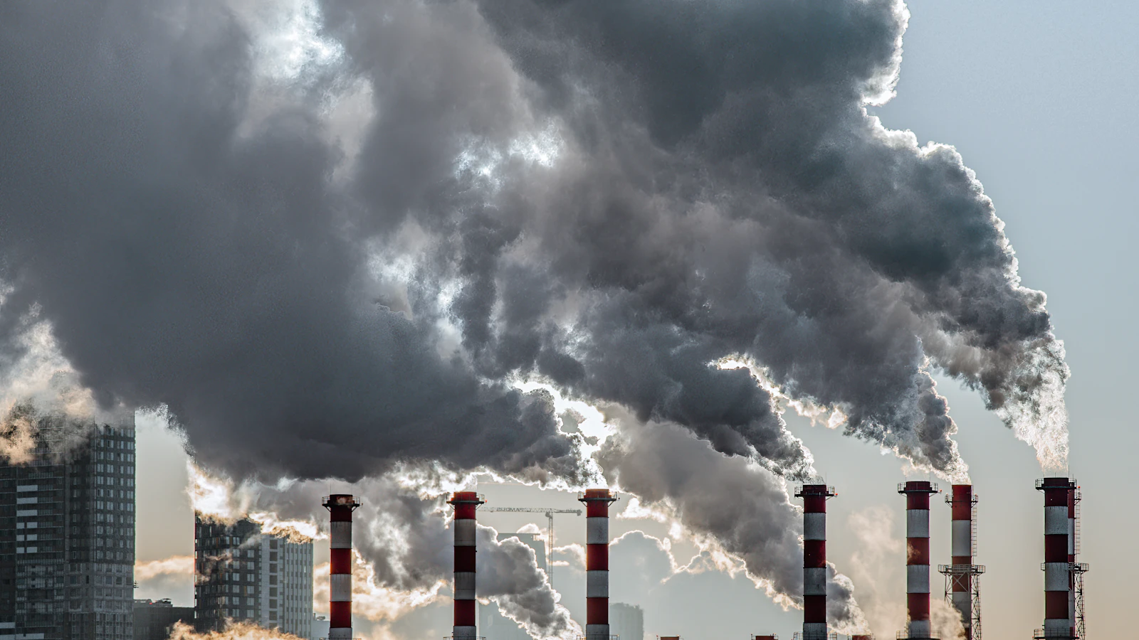 smoke billows from the stacks of industrial buildings