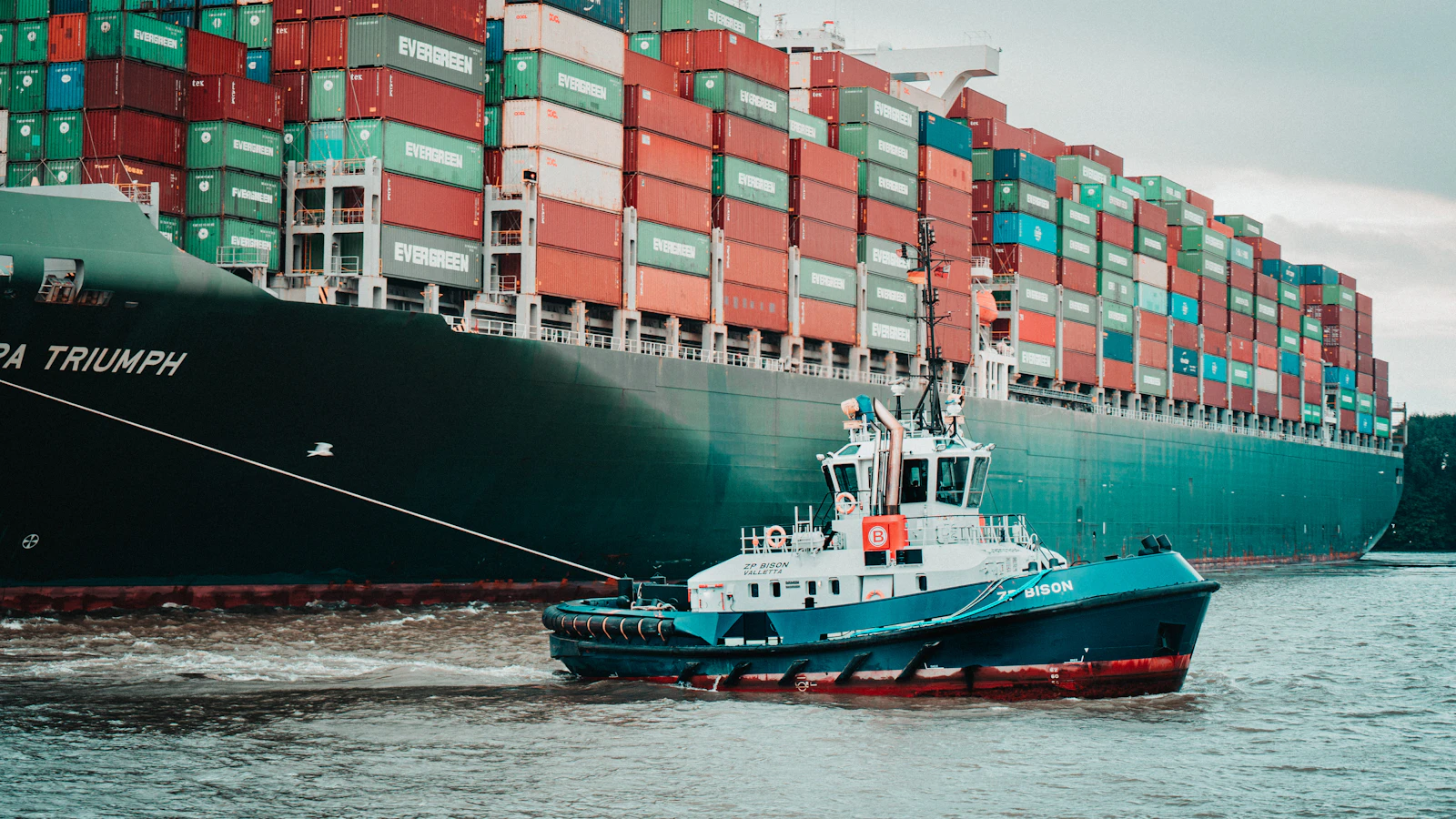 a tug boat pulling a large container ship